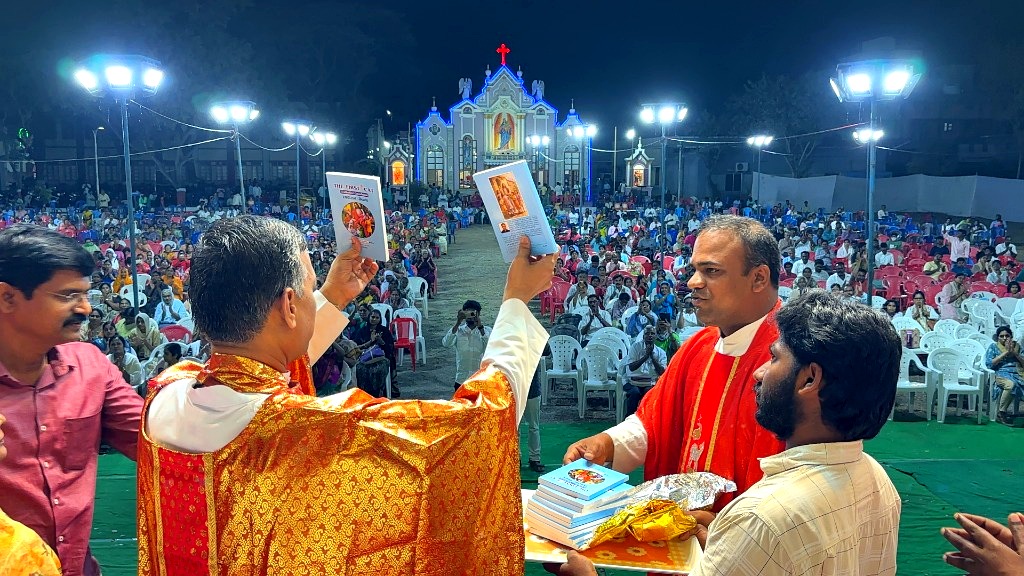 Priests showing the First Cat catechism book to the community